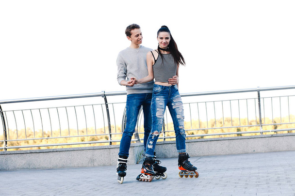 Beautiful sweet couple riding on roller skates holding hands - Foto, Imagen