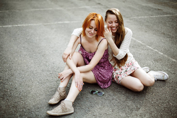 Two teen girls sitting on the playground - Fotó, kép
