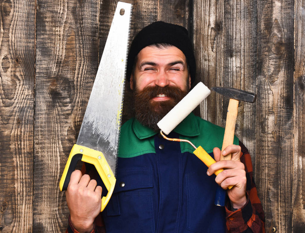 bearded builder holding various building tools with happy face - Foto, Bild