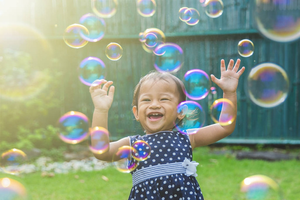 kleines Mädchen versucht Seifenblasen zu fangen - Foto, Bild
