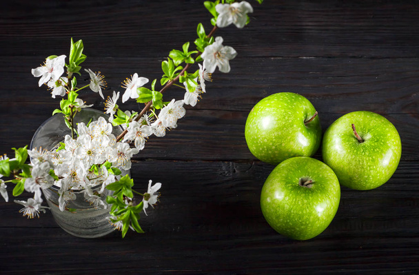 Green apples with blossoms on wooden table - Фото, зображення