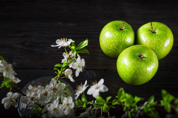Green apples with blossoms on wooden table - Valokuva, kuva
