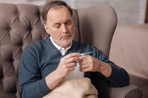 Old man checking his temperature at home - Фото, изображение