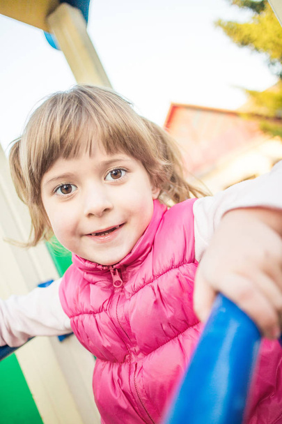 Cute little girl sitthing on a playground slide. - Foto, imagen