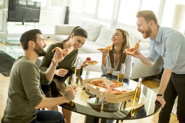 Friends eating pizza in the modern interior - 写真・画像