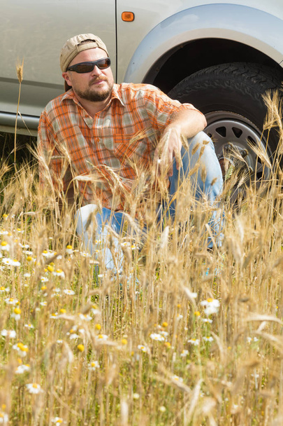 Agricultor en gafas de sol sentado cerca de coche
 - Foto, imagen