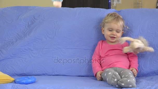Chuva de brinquedos macios caindo em menina loira bonito sentado no sofá. Sonho de criança se tornou realidade
 - Filmagem, Vídeo