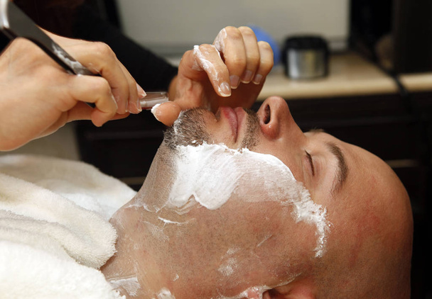 El hombre está afeitado por una barba
 - Foto, Imagen