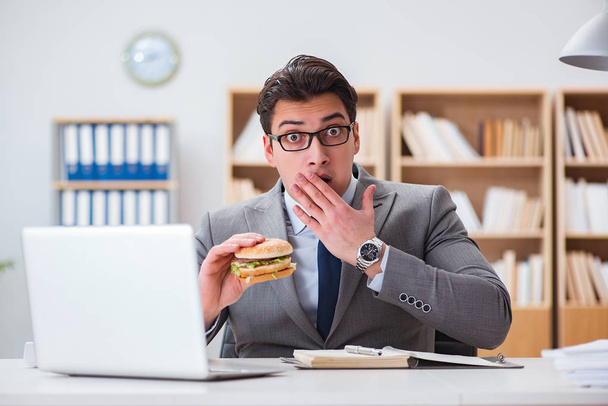 Hungry funny businessman eating junk food sandwich - Fotoğraf, Görsel