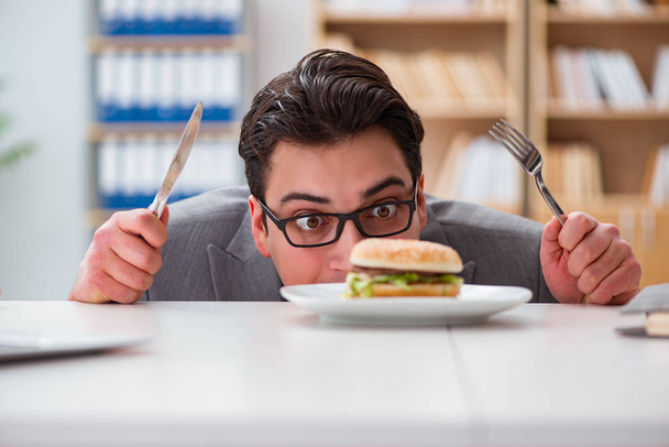 Hungry funny businessman eating junk food sandwich - Фото, изображение