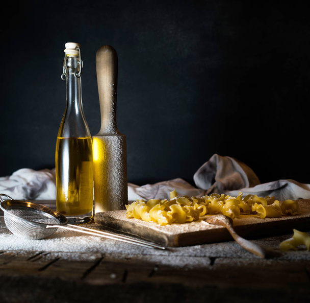 Pasta, olive oil on a wooden table. Dark background - Fotoğraf, Görsel