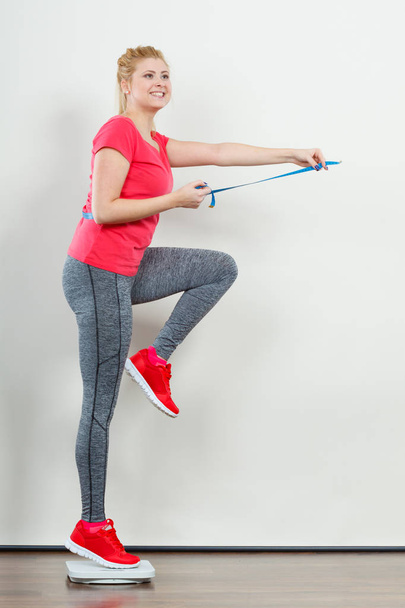 Woman wearing sportswear standing on weight machine - Foto, Imagen