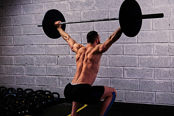 Athletic shirtless man doing squats - Foto, Bild