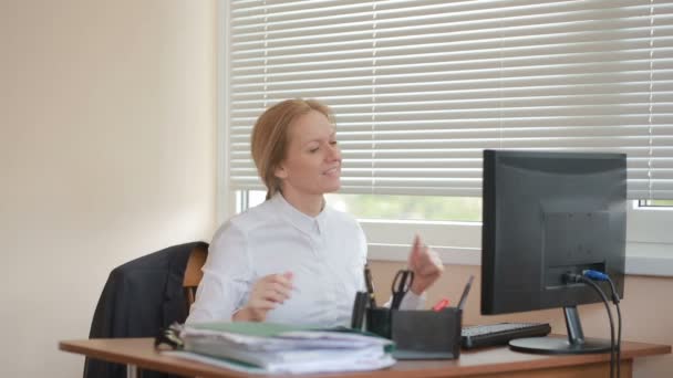 Ένα θηλυκό manager είναι κουρασμένος από την εργασία σε ένα τραπέζι στο γραφείο και χορεύει - Πλάνα, βίντεο