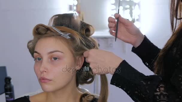 professioneller Friseur macht Frisur für junge hübsche Frau - macht Locken - Filmmaterial, Video