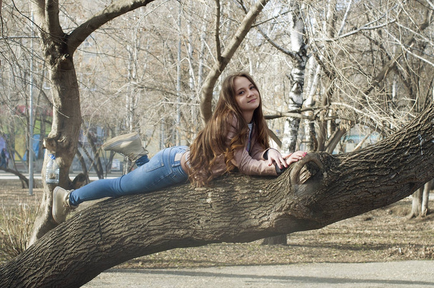 The beautiful Russian girl with long hair lies on a tree and smi - Zdjęcie, obraz