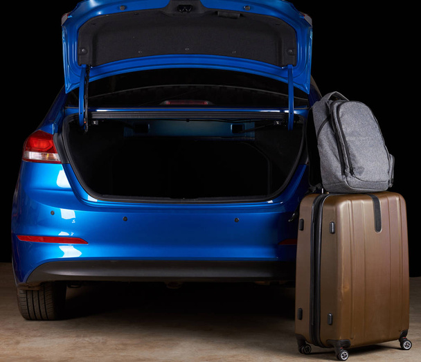 Luggage bags stand next to open car trunk - Foto, Imagen
