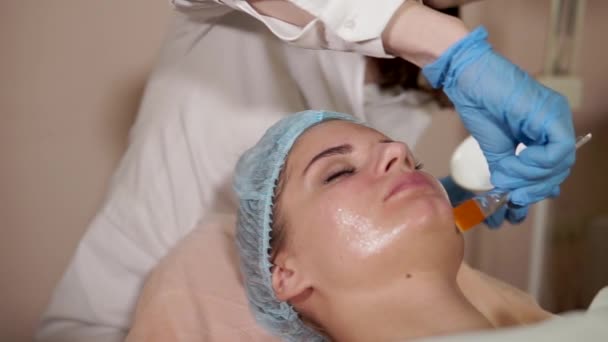Procedimiento de cosmetología. Mujer recibiendo máscara facial aplicar por cosmetólogo
. - Imágenes, Vídeo