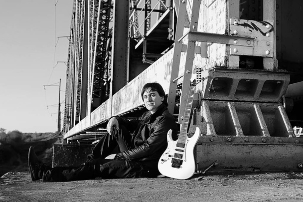 Homme monochrome avec guitare électrique dans le paysage industriel
 - Photo, image