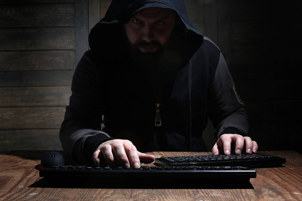 хакер в чорному капюшоні в кімнаті з дерев'яними стінами
 - Фото, зображення