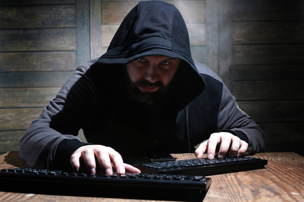 Hacker v černé kápi v místnosti s dřevěnými stěnami - Fotografie, Obrázek