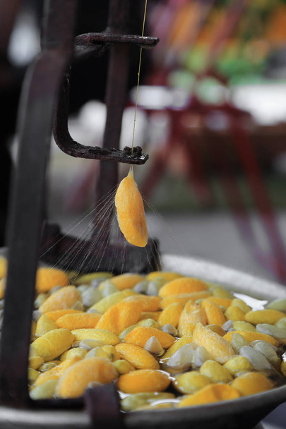Кокон из золотого червя варится для молотильных волокон шелка
. - Фото, изображение