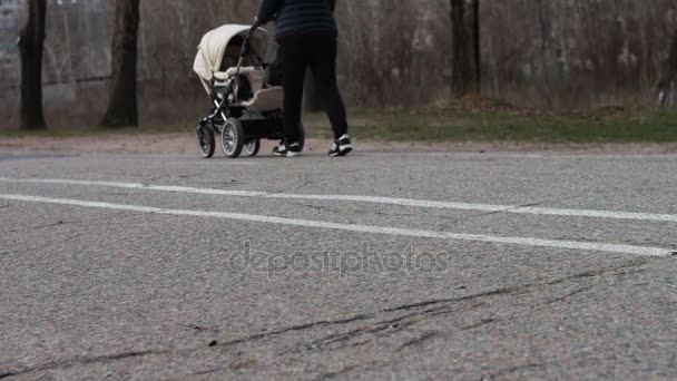 Jonge moeder met een witte stroller.walking voeten op de stoep. - Video