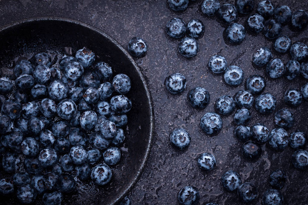  fresh picked blueberries on black stone background - 写真・画像