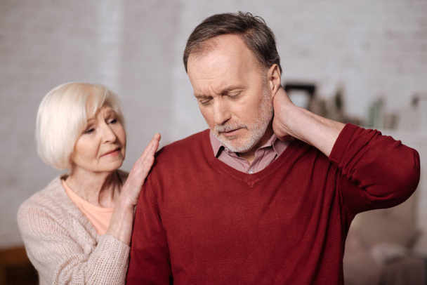 Closeup of elderly woman supporting husband with neck ache - Photo, image