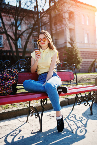 Young teenage girl sitting on bench with ice cream at hands, wea - Fotoğraf, Görsel
