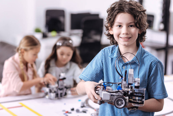 Delighted boy holding robot at school - Foto, imagen