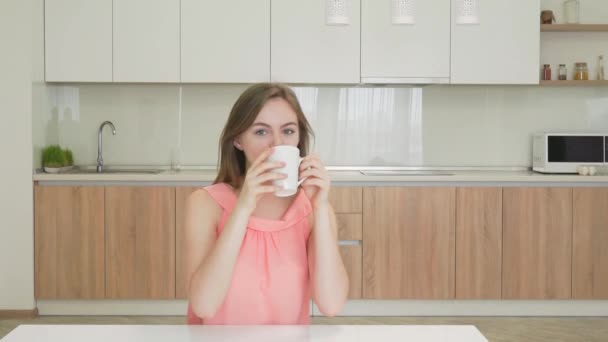 Νεαρή γυναίκα πίνοντας τσάι και να χαμογελά στη φωτογραφική μηχανή - Πλάνα, βίντεο