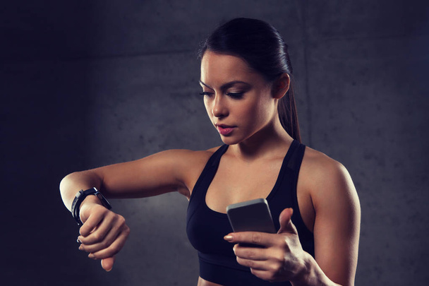 woman with heart-rate watch and smartphone in gym - Fotó, kép