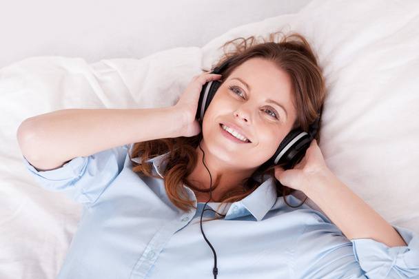 Woman relaxing listening to music in bed - Foto, afbeelding
