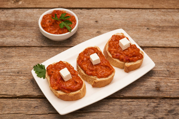gebratener Paprika-Dip auf Brot mit Feta-Käse auf Holzbrett - Foto, Bild