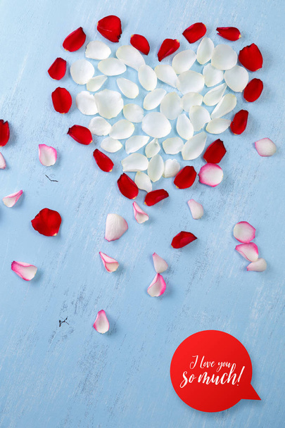 Heart of rose petals on blue wooden board. - Foto, imagen