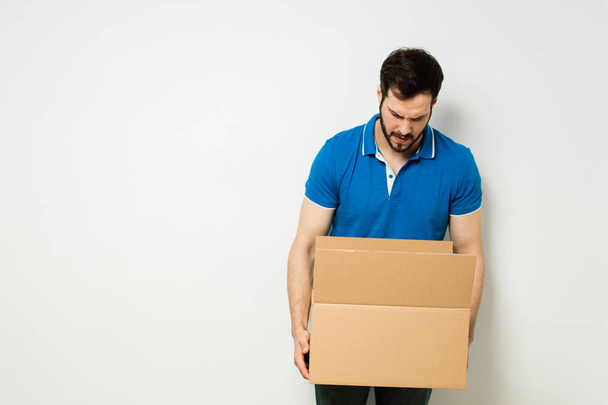 young man with a cardboard box in his arms - Foto, afbeelding