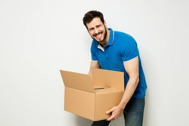 νεαρός άνδρας με ένα κουτί από χαρτόνι στην αγκαλιά του - Φωτογραφία, εικόνα
