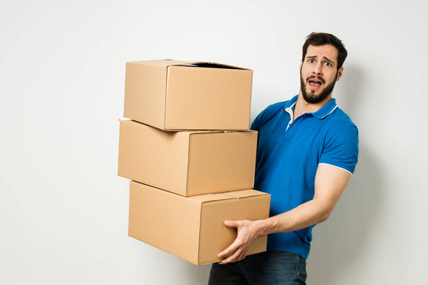 young man with a cardboard box in his arms - Фото, зображення