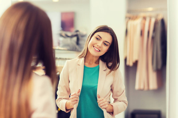 happy woman posing at mirror in clothing store - Foto, Imagem