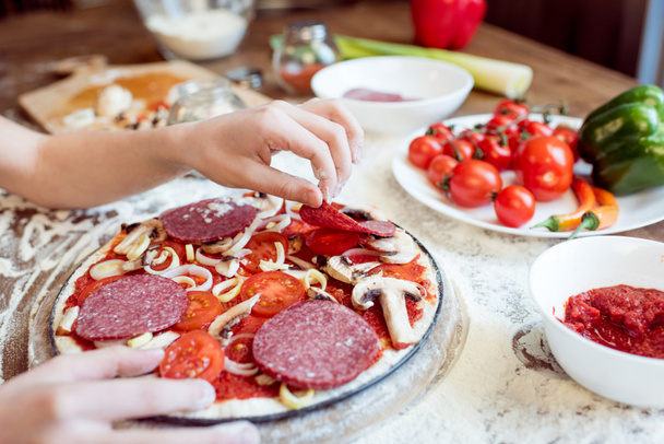 child putting sausage on pizza - Foto, immagini