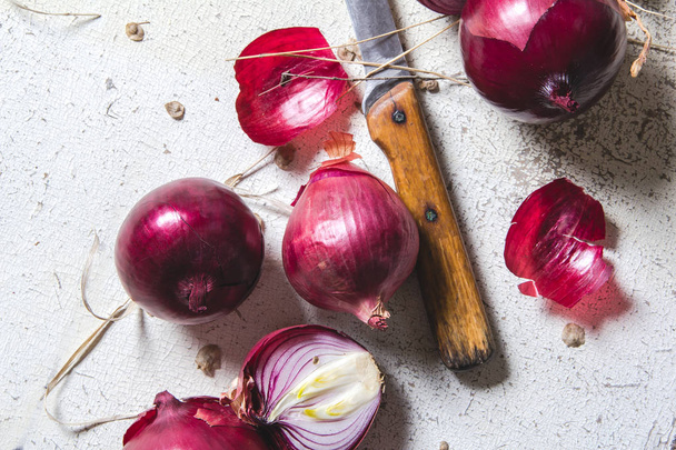 Several kinds of different onion bulbs lying on an old wooden table painted in white. - Foto, imagen