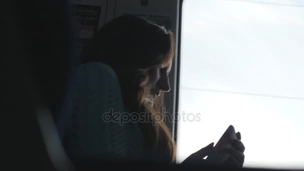 junges Mädchen telefoniert während der Zugfahrt. Frau, die in der Bahn unterwegs ist und mit dem Smartphone spricht. Frau schaut zum Fenster und spricht mit Handy - Filmmaterial, Video
