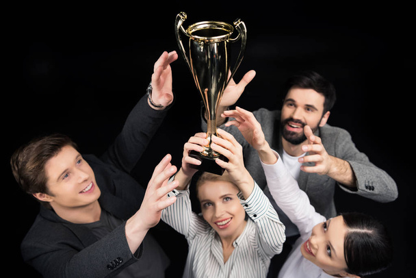 business people holding goblet - Foto, afbeelding