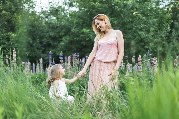 Mom with daughter holding hands in pink flowers - Foto, Imagem