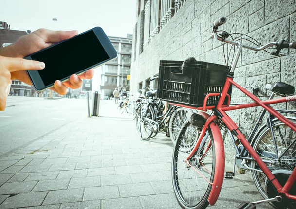 hands with phone near the bike in the city - Φωτογραφία, εικόνα