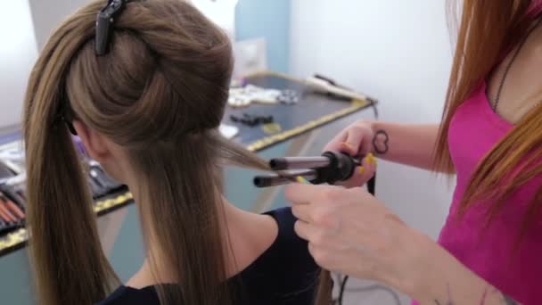 Profesjonalny salon fryzjerski robi fryzurę dla pretty teen dziewczyna - Dokonywanie loki - Materiał filmowy, wideo