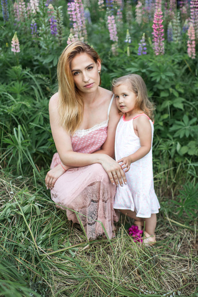 Mom and daughter in a blooming garden at summer - Foto, immagini
