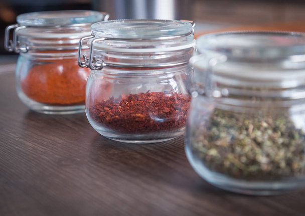 Garlic and spices in glass jars on wooden background  - Zdjęcie, obraz