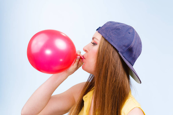 Female teenager inflating red balloon. - Фото, зображення